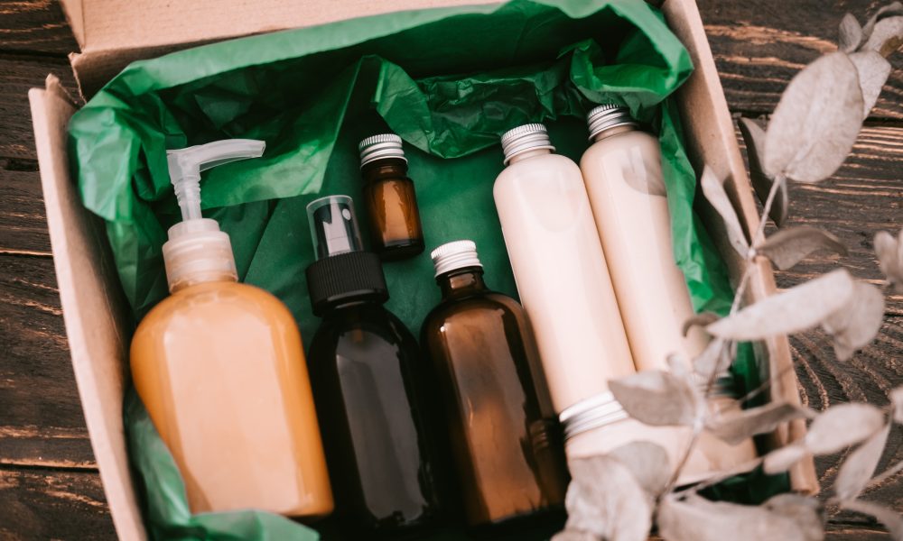 Beauty box with bottles of natural cosmetics, wrapped in green paper. Blogger hair and body care routine, salon treatments